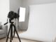 Photographer arranging skincare products on a clean white surface for e-commerce shoot